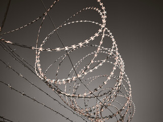 Barbed wire against dark grey sky. 
