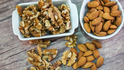 Almendras y Nueces en cuencos blancos sobre madera veteada