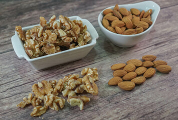 Nueces y Almendras en cuencos blancos sobre madera veteada