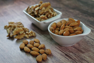 Nueces y Almendras en cuencos blancos sobre madera veteada