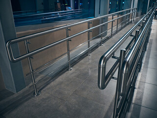Ramp with chrome colored railings for disabled people using wheelchair at airport. Accessible environment for people with disabilities