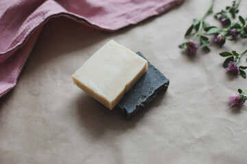 Natural organic soap with flowers and pink towel on craft paper background top view with copyspace