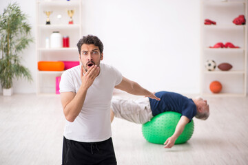 Young male instructor and old man doing sport exercises