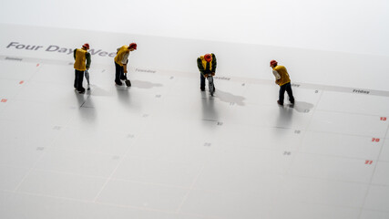 Printed calendar for a 4 day working week showing weekend days in red with small workmen working in...