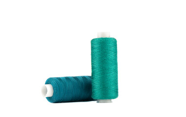 Spools of blue and green thread isolated on white background.