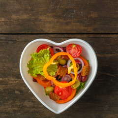 Healthy vegetable salad in a salad bowl on a wooden table.