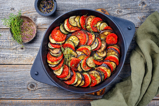 Modern style traditional French ratatouille with tomatoes, eggplant and zucchini served as top view in a rustic cast-iron skillet
