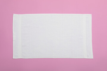 White beach towel on pink background, top view