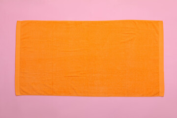 Orange beach towel on pink background, top view