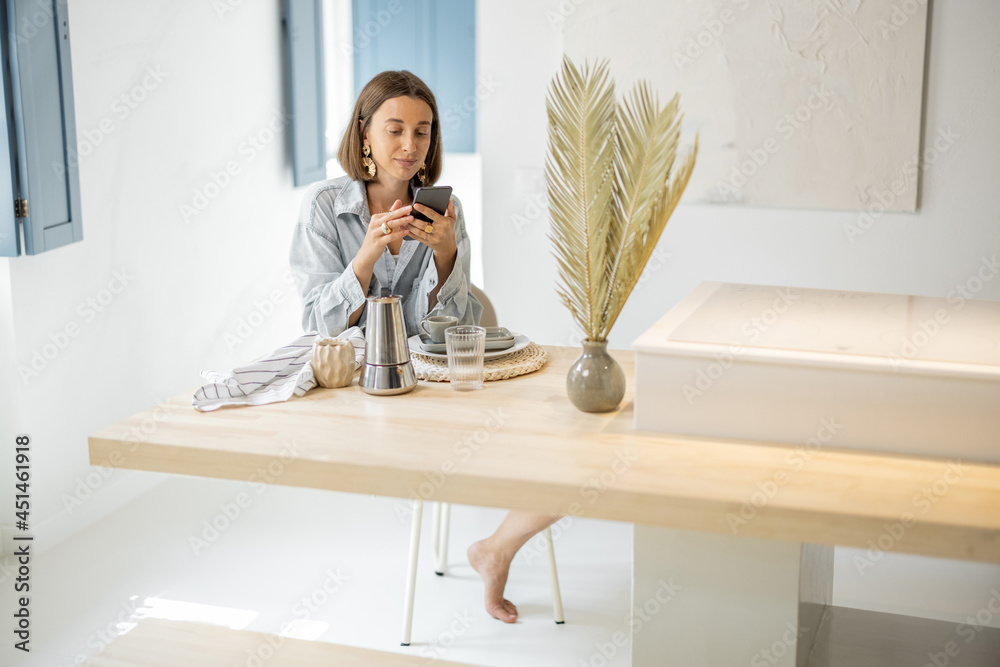 Wall mural Young woman using cell phone at home, relaxing and having leisure time at modern bright apartment