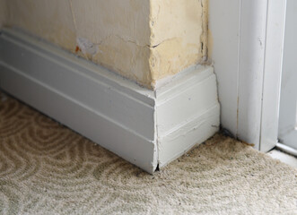 Old white plinth with carpet in the hotel.Moulding in the corner. Details in the interior.