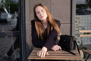 pretty brunette woman sitting by wooden table outside. feminine. millennial people. lady on coffee break