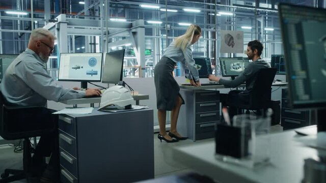 Car Factory Office: Project Manager Talks to Engineer Working on Computer. CAD Software, 3D Turbine Engine, Electric Car. Automated Robot Arm Assembly Line Manufacturing Vehicles. Wide Tracking Shot