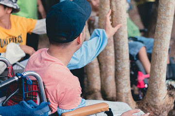Smart handicapped teenager boy on wheelchair and friends on nature outdoors with sensory therapy in hiking, Lifestyle of disabled kids with school of special children.