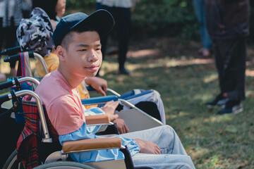 Smart handicapped teenager boy on wheelchair and friends on nature outdoors with sensory therapy in hiking, Lifestyle of disabled kids with school of special children.