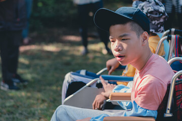 Smart handicapped teenager boy on wheelchair and friends on nature outdoors with sensory therapy in hiking, Lifestyle of disabled kids with school of special children.