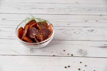 Homemade jerked dried meat or biltong with spices on a wooden background. Beer snack concept....