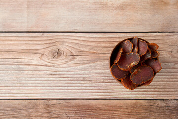 Homemade jerked dried meat or biltong with spices on a wooden background. Beer snack concept....