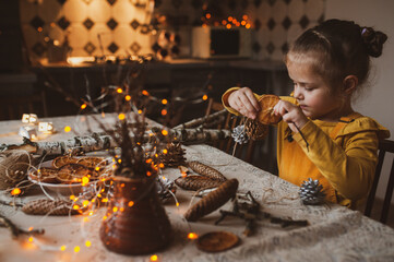 A cute sweet girl makes Christmas decorations from dried oranges, twigs and cones. Crafts for the holiday