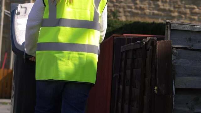 Waste collector wheels waste bin in urban street