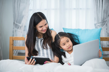 children and girl sisters having fun to watching online video on laptop computer cyberspace, childhood people family or young mother and little daughter are happy together at home with technology