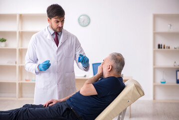 Obraz premium Old male patient visiting young male doctor in vaccination conce
