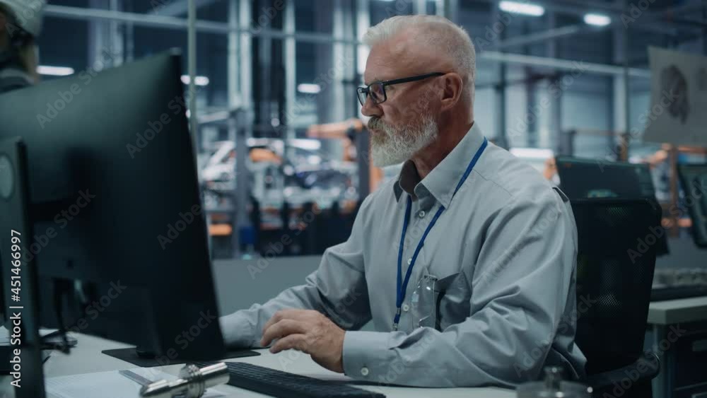 Poster car factory office: portrait of male engineer working on computer. automated robot arm assembly line