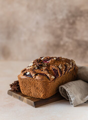 Homemade spicy plum cake decorated with almond on a wooden serving board, concrete background. Loaf cake with plum, spices and almond.