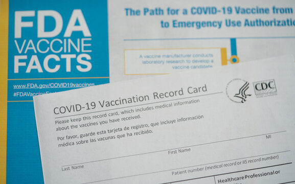 Washington, DC, USA - August, 16, 2021: COVID - 19  Vaccination Record Card Next To The FDA Vaccine Facts.