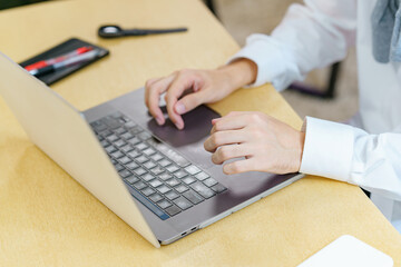 カジュアルな空間でノートパソコンを使う若い男性のクローズアップ