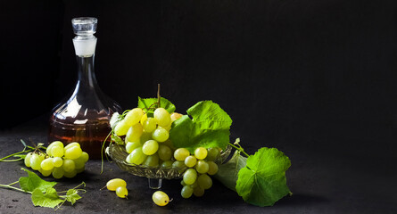 Fresh ripe grapes and decanter with grape juice on black background