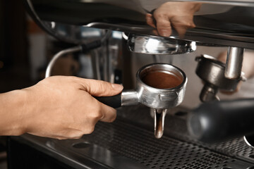 Barista making espresso using professional coffee machine, closeup