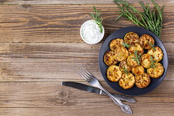 Fried slices of zucchini with sour cream sauce. Courgettes with herb for dinner on natural wooden background