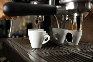 Barista making espresso using professional coffee machine, closeup