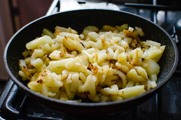 Cook delicious fried potatoes on the stove in the kitchen. Complete meal.