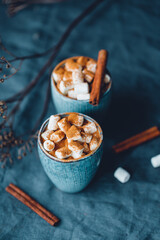 Hot chocolate with marshmallow and cinnamon in blue ceramic cups on a table. The concept of cosy holidays and New Year.