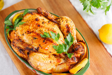 Whole roasted chicken with fresh parsley and lemon wedges in a festive dish