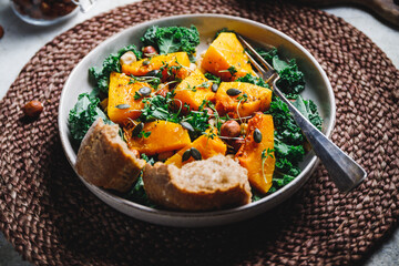 Season salad with grilled pumpkin, kale, chickpea, pepitas and nuts. Autumn vegetarian healthy recipe.