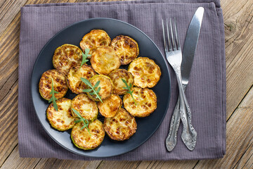 Fried slices of zucchini with sour cream sauce. Courgettes with herb for dinner on natural wooden background