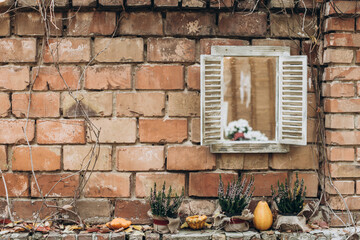 Autumn porch decor. Garland of autumn leaves, pumpkins and pots with plants on a brick facade background. Harvest concept