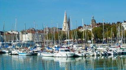Fototapeta na wymiar La Rochelle, France - September 9. 2016: View on harbor with motor and sail yachts, old cityscape against blue summer sky background