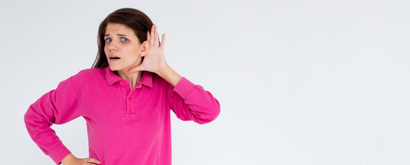 I cant hear you. Beautiful young woman listening gossips and holding her hand near the ear while isolated on white