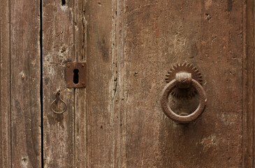 Medieval handle, hanging on a medieval brown door, touched by time and weather 