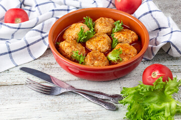 Meatballs in tomato sauce in a bowl on wooden table.