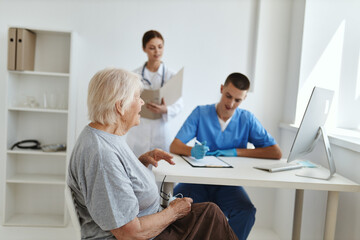 an elderly woman sitting at a doctor's appointment with a nurse treatment diagnostics