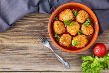 Meatballs in tomato sauce in a bowl on wooden table.