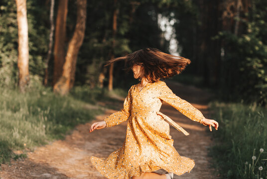 Beautiful little girl spinning and dancing in the woods in the summer