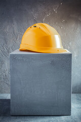 Construction helmet on concrete cube or cement block background texture. Work cap at table