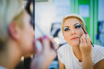 Woman Applying Eye Shadow In Front Of Mirror At Beauty Salon