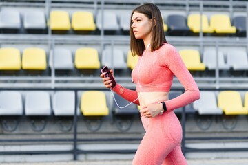 Young woman running during sunny morning on stadium